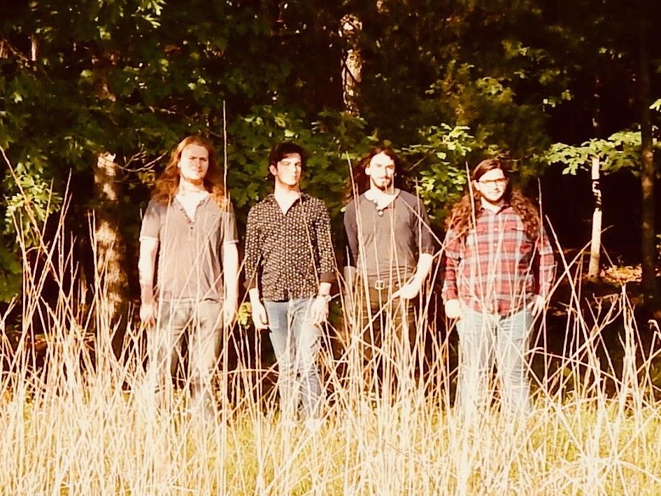 The four band members standing in a field. Serves mainly as a page break in between sections.