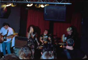 picture of four band members performing in small dark room