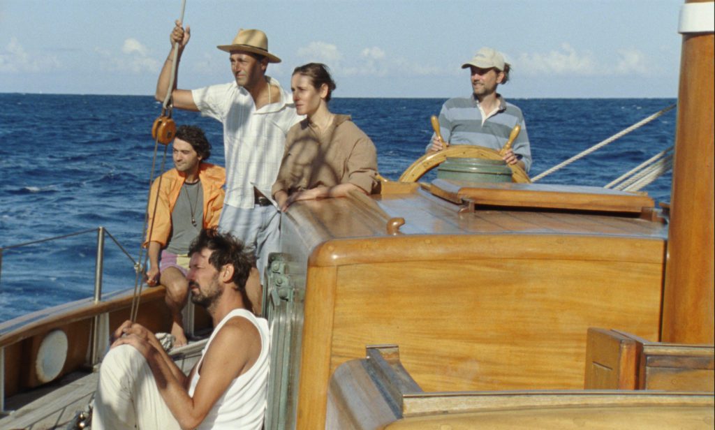 A group of people stand on a boat, looking out into the water